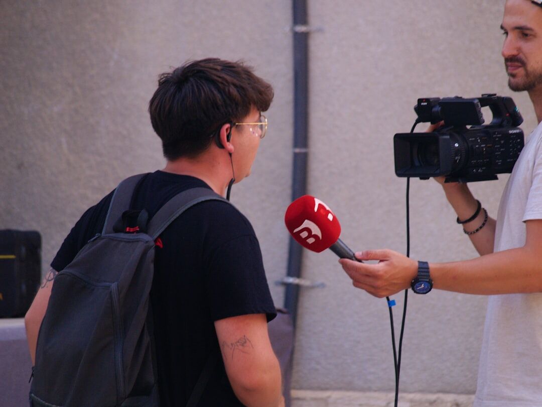 News crew filming a live outdoor report with camera and microphone